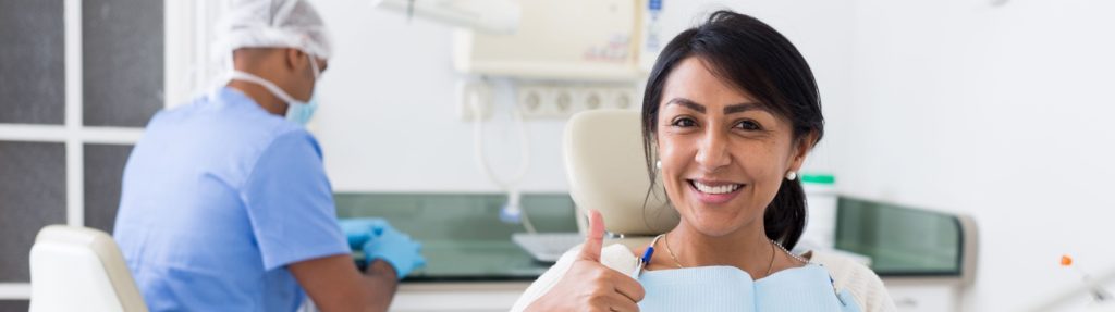Woman giving her a thumbs up during her dental appointment