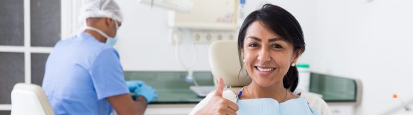 Woman giving her a thumbs up during her dental appointment