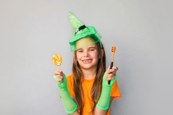 young girl holding a tooth brush and candy on Halloween